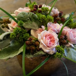 Pink roses arranged in a low bowl with green accents