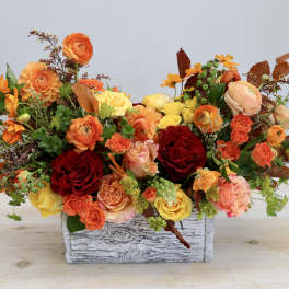 Mixed orange, yellow, and red floral arrangement in a rustic wooden box