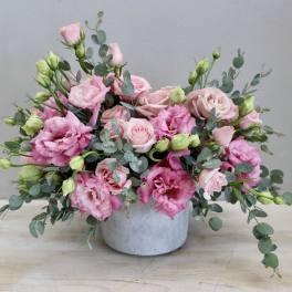Pink roses and lisianthus in a gray vase with eucalyptus