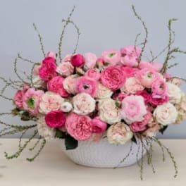Low centerpiece of pink and white blooms in a white ceramic bowl