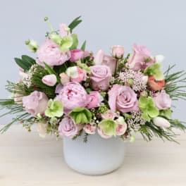 Low white vase filled with pink roses, peonies, tulips and green hydrangea blooms