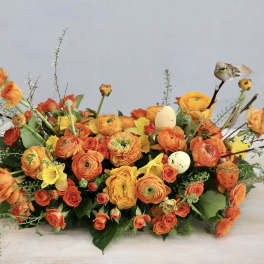Orange and yellow floral arrangement with decorative eggs and bird accents