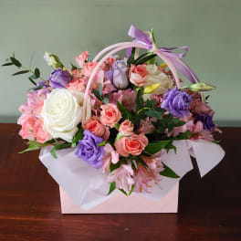 Pastel bouquet of roses and lisianthus in a pink gift box with ribbon handle