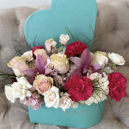 Mixed bouquet of pink and white roses, orchids, and carnations in a turquoise box