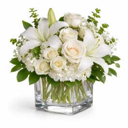White roses and lilies arranged in a clear glass vase