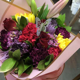 Colorful bouquet with roses, lilies, chrysanthemums, and carnations in pink wrap