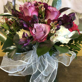 Bouquet of pink and purple roses with white carnations in a glass vase
