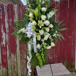 Tall white floral standing spray with ribbon on an easel