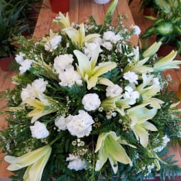 White lilies and carnations in a low, round arrangement