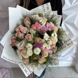 Bouquet of pink and white roses with mixed blooms wrapped in printed paper