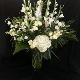 White floral arrangement in a clear glass vase with tall stems and lilies