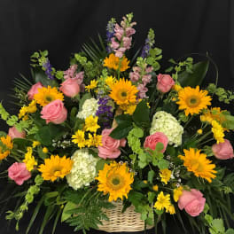 Basket arrangement of pink roses, sunflowers, and white hydrangeas