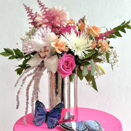 Mixed bouquet in a tall glass vase with butterflies at the base
