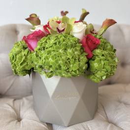 Bouquet of pink and white roses with green hydrangeas in a gray box