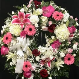Heart-shaped floral wreath with pink and white flowers on a black stand