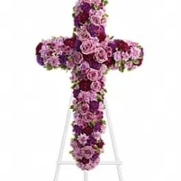 Cross-shaped floral arrangement in pink and purple flowers on an easel