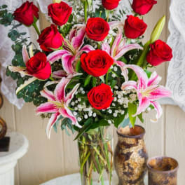 Bouquet of red roses and pink lilies in a clear glass vase