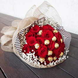 Bouquet of red roses with gold-wrapped chocolates and baby’s breath