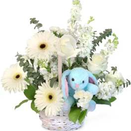 White flowers in a basket with a blue plush bunny