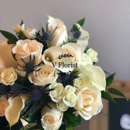 Bouquet of cream roses, white calla lilies, and blue thistle