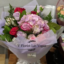 Bouquet of pink and red roses with hydrangea in lavender wrap
