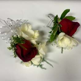 Red and white rose corsage and boutonniere with ribbon and pearl pins