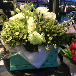 White and green floral arrangement in a turquoise polka-dot box