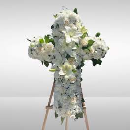 White floral cross arrangement on a wooden easel