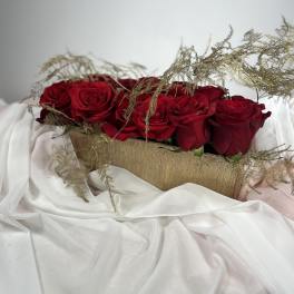 Red roses arranged in a gold rectangular container with airy filler