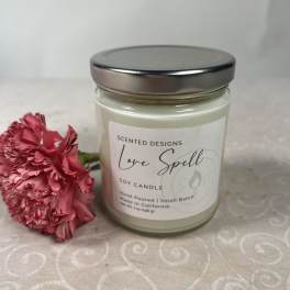 Soy candle in a glass jar beside a pink carnation