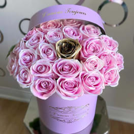 Round hatbox of light pink roses with a single gold rose in a lavender cylinder box