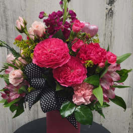 Pink and magenta bouquet in a tall vase with a polka-dot ribbon