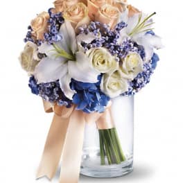 Bouquet of peach and white roses with blue flowers in a glass vase