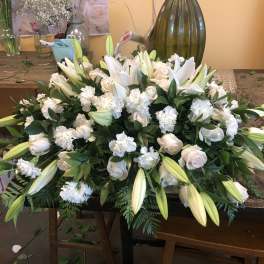 Large white floral arrangement with lilies and roses on a table