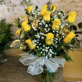 Yellow roses with baby's breath in a glass vase and white bow