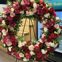 Large floral wreath with red, pink, and white blooms on a black stand