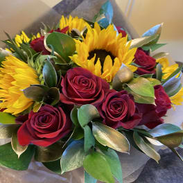 Bouquet of red roses and yellow sunflowers wrapped in paper
