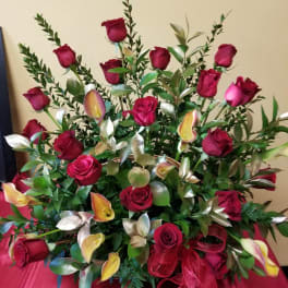 Red rose arrangement with calla lilies and greenery in a vase
