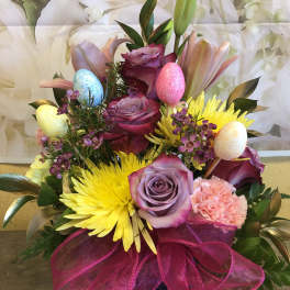 Mixed bouquet with roses, lilies, and bright yellow blooms in a vase
