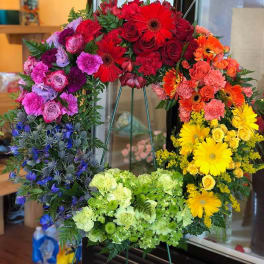Colorful floral wreath on a stand with red, pink, orange, yellow, and green blooms