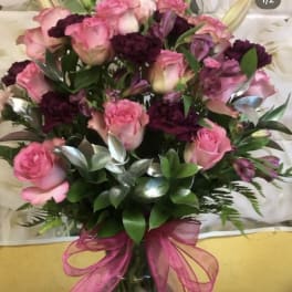 Bouquet of pink roses and dark purple flowers tied with a pink ribbon
