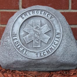 Gray emergency medical technician memorial stone against a brick wall
