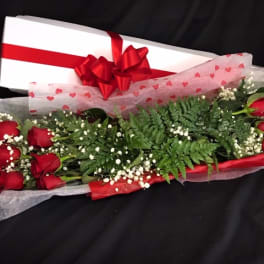 Long bouquet of red roses with baby's breath and a gift box tied with a red bow