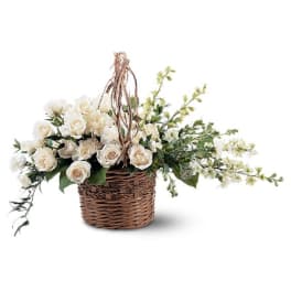 White roses in a wicker basket with trailing greenery