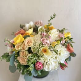 Mixed bouquet of pastel roses, tulips, and white blooms in a vase