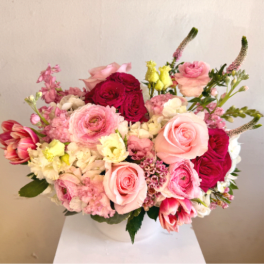 Low pink and white flower arrangement with roses, ranunculus, tulips, and hydrangeas in a white bowl vase
