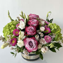 Pink and white roses with green hydrangeas in a round container