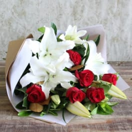 Bouquet of white lilies and red roses wrapped in paper