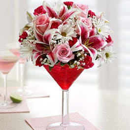 Pink and white flower arrangement in a red martini glass vase