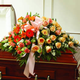 Large floral spray with roses, gerbera daisies, and lilies on a casket